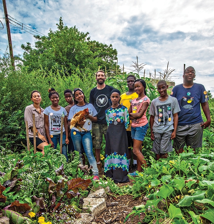 PhillyEarth permaculture students at the Village of Arts and Humanities stand with their teacher, Jon Hopkins (center) in the middle of their garden |&nbsp;photos by Jared Gruenwald