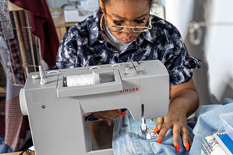 A Grant Blvd seamstress stitches a label into a denim jacket. The company currently has four employees. | Photography by Milton Lindsay