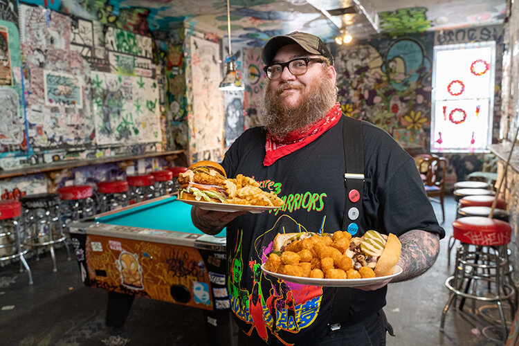 Ryan Pasquale, director of food at Tattooed Mom poses with two of its vegan plates. Portrait by Milton Lindsay.