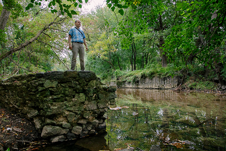 Man standing on old stone structure above creek