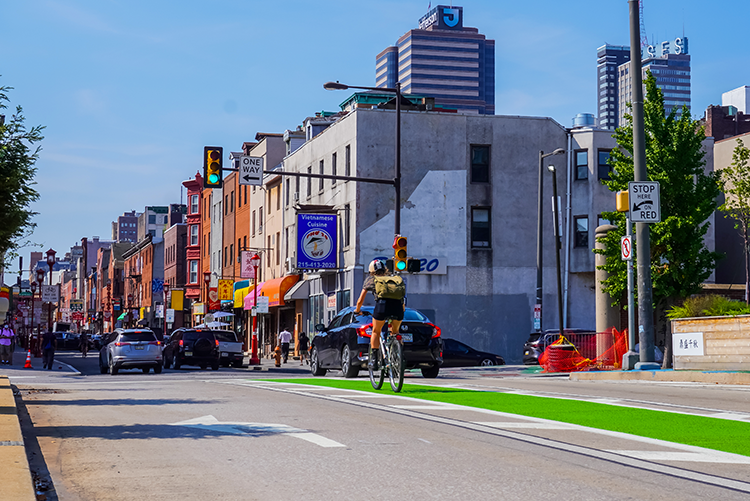 an urban street with cyclist riding down a green bike lane