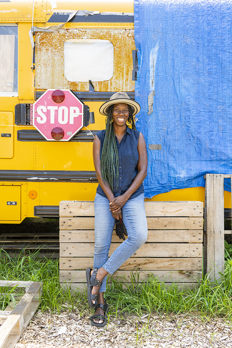 Dominique London stands beside her rehabilitated “skoolie” on her family’s land in Southwest Philadelphia. Photography by Drew Dennis.