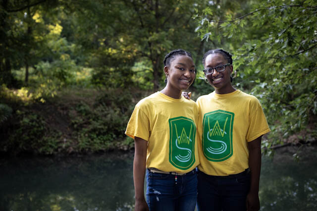 Twin sisters Imani (left) and Nia Mitchell stand by Cobbs Creek, which they’ve been studying and protecting as Watershed Stewards.Photographs by Rachael Warriner
